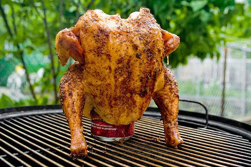 A whole chicken with a cola can in its cavity, roasting vertically over a grill. 