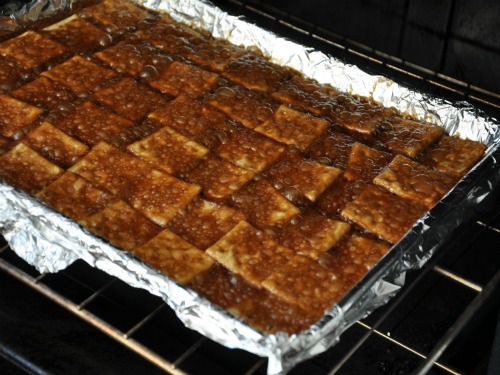 A foil-lined baking sheet of saltine crackers covered with brown sugar that's hot and bubbling.