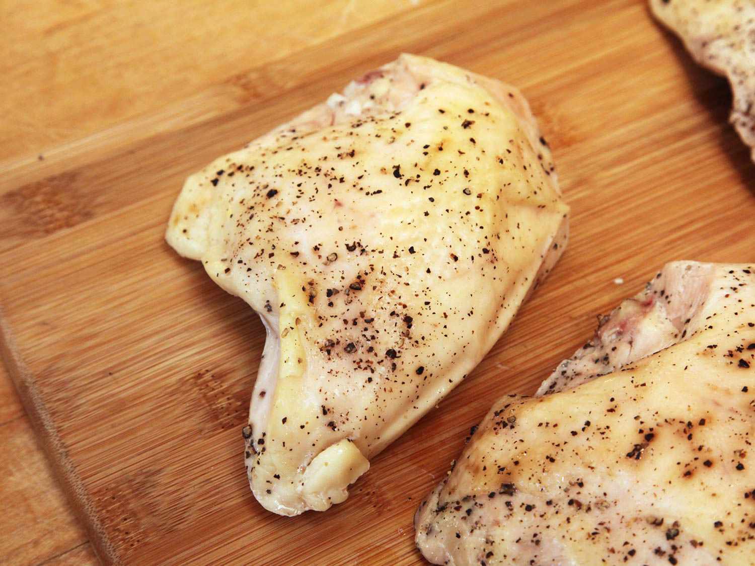 Cooked sous vide chicken breast on a wooden cutting board.