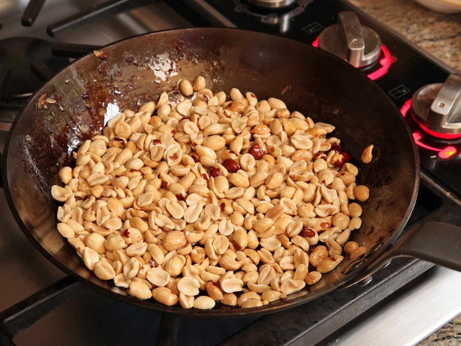 Toasting peanuts with oil in a skillet. 