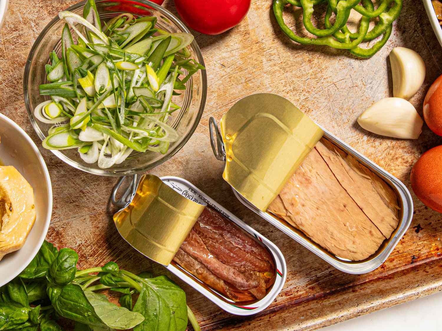 An assortment of sliced vegetables and opened cans of fish on a tray