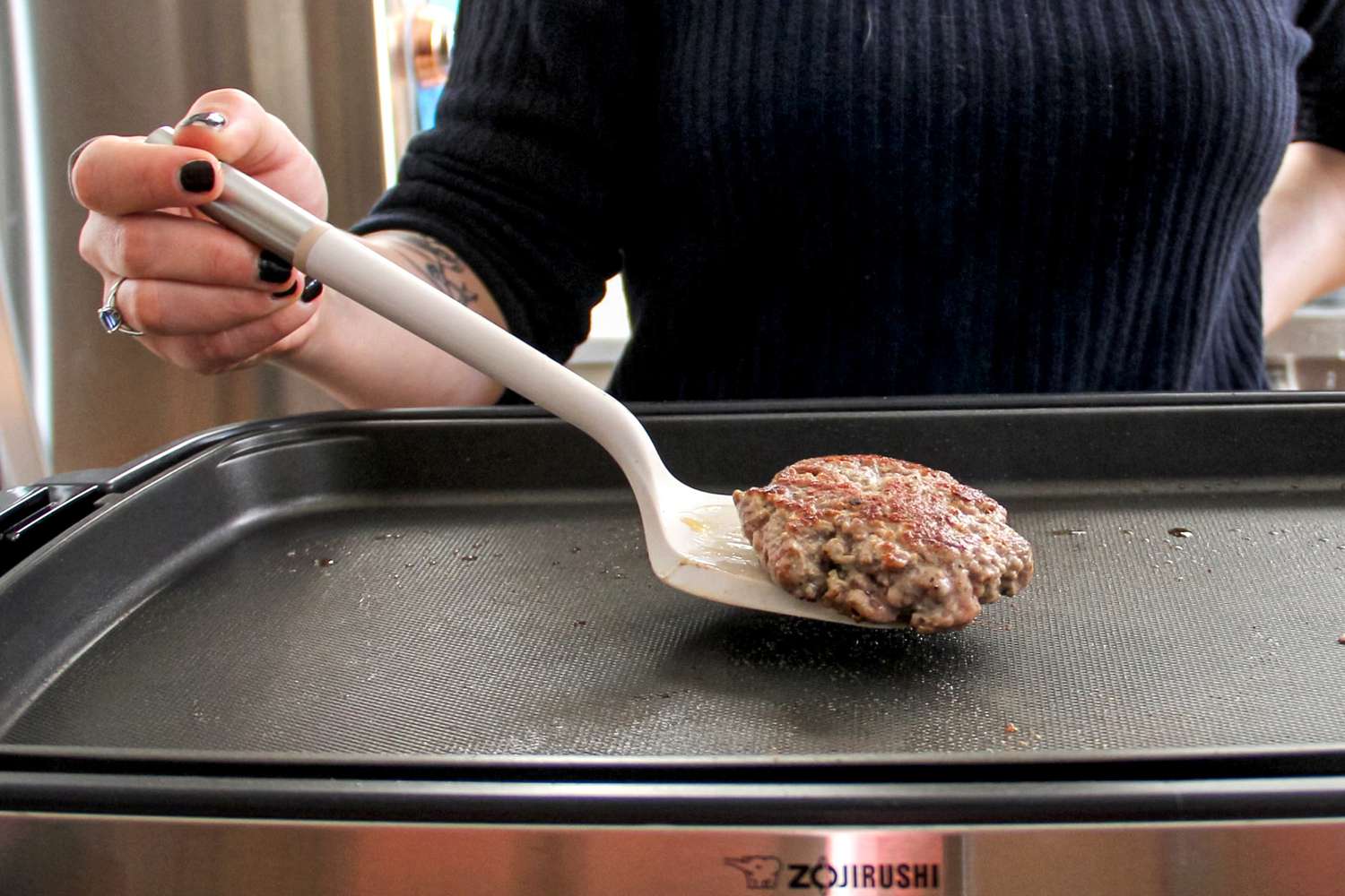 A person using the Material Soft-Edged Turner to flip food