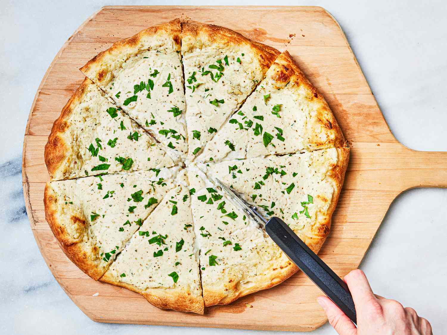 Overhead view of slicing white pizza
