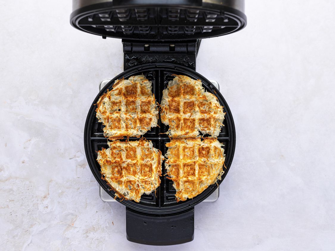 Cooked waffle iron has browns inside of the waffle iron.