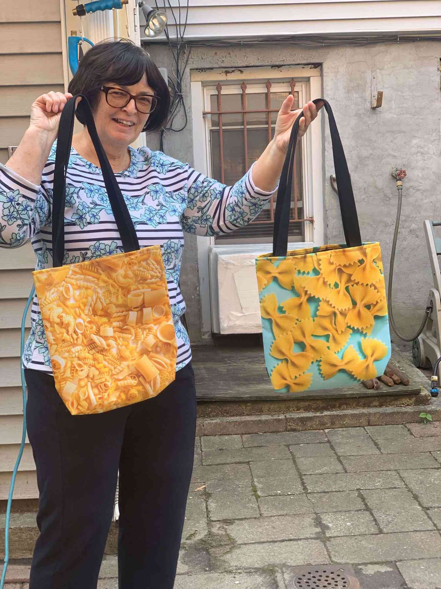 Vicky's mother holding up pasta themed tote bags