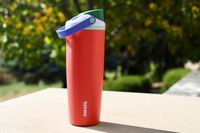 An Owala FreeSip Sway (in Summer Harvest colors) photographed outside against a lush tree background.