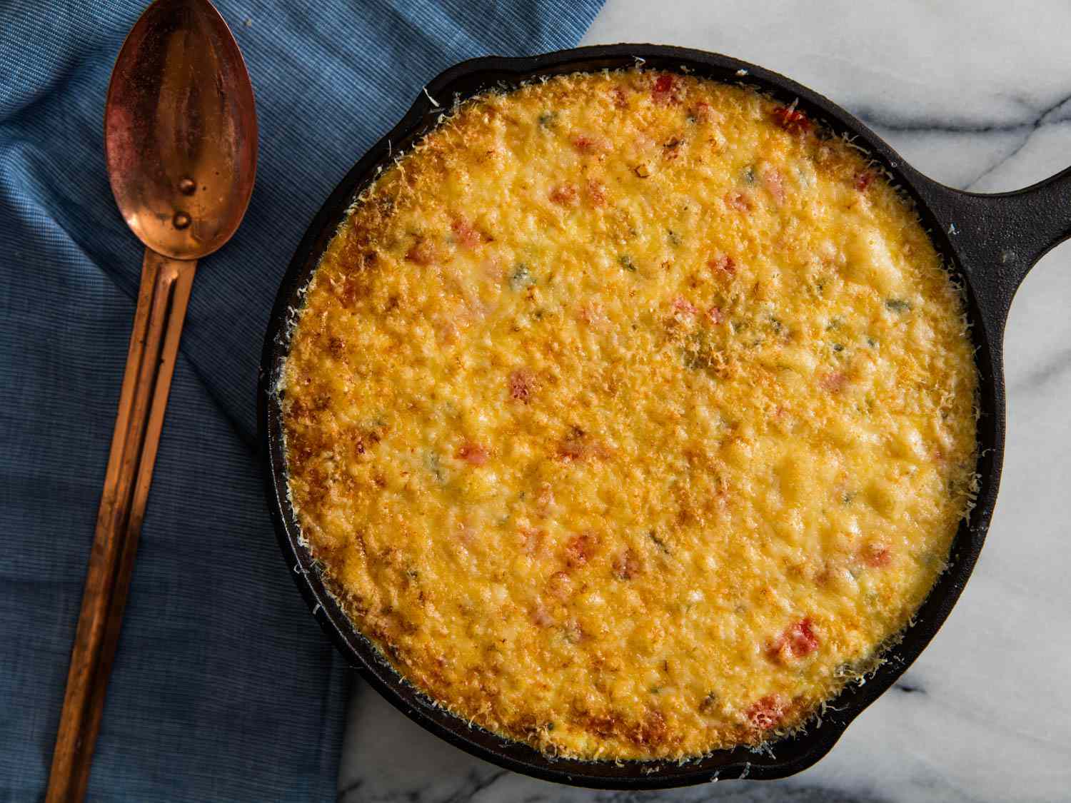 A cast iron skillet full of corn casserole, baked to golden perfection.
