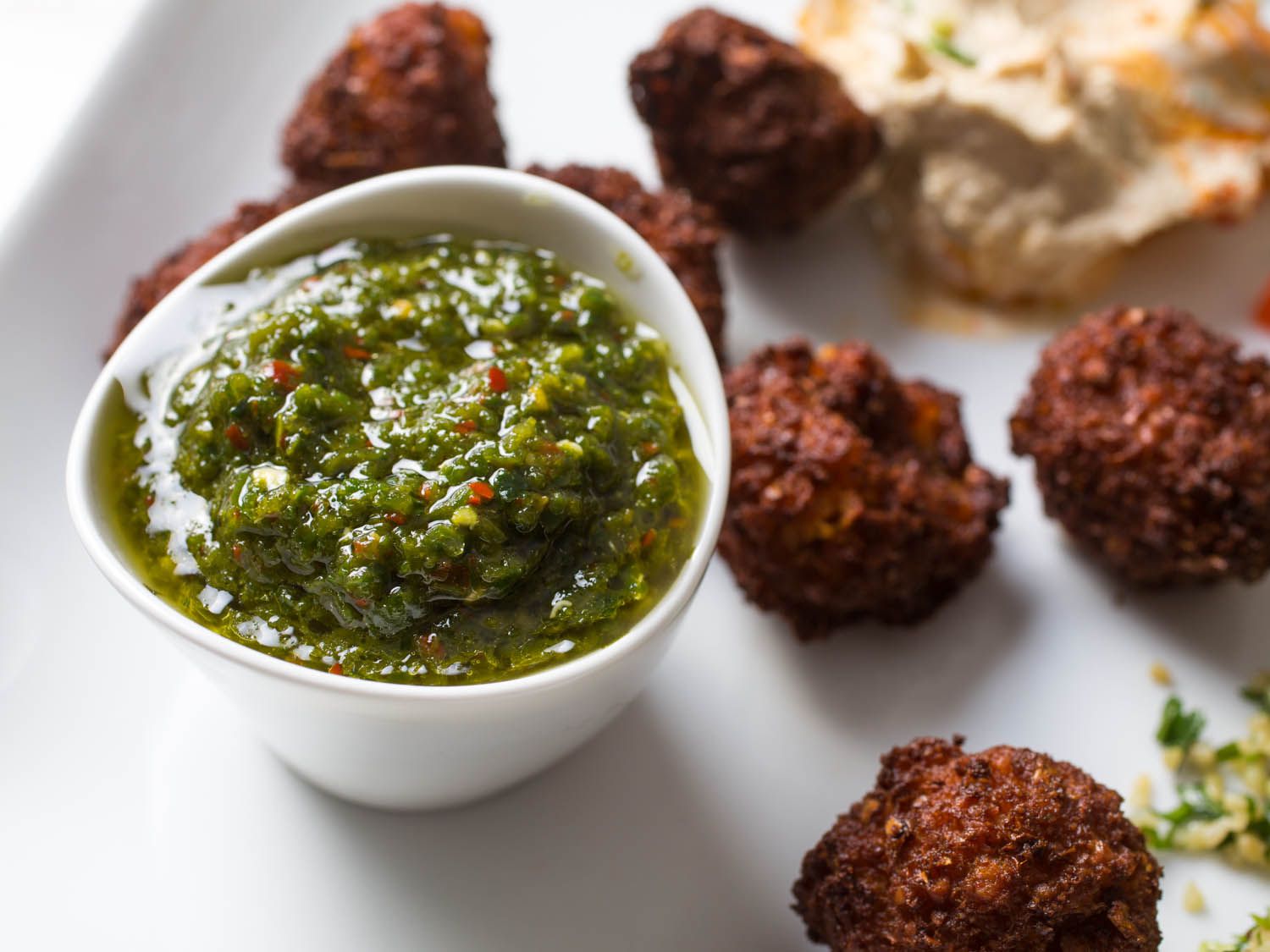 A small ramekin of zhug, which is a Yemeni green chile and herb sauce.