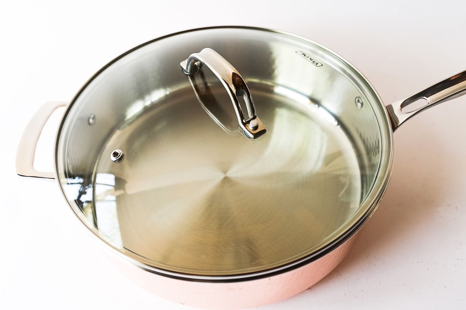 A lidded stainless steel cooking pan with a glass lid and a handle