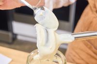 A person spoons puree from the blade of the Hamilton Beach 2-Speed Hand Blender