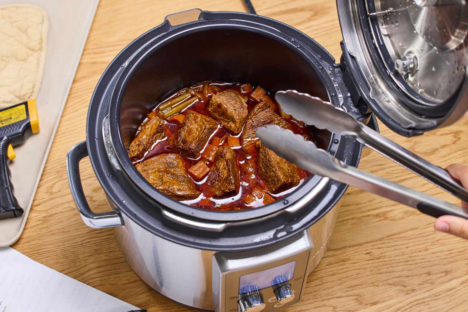 A person stirs cooking meat in the Breville the Fast Slow Pro