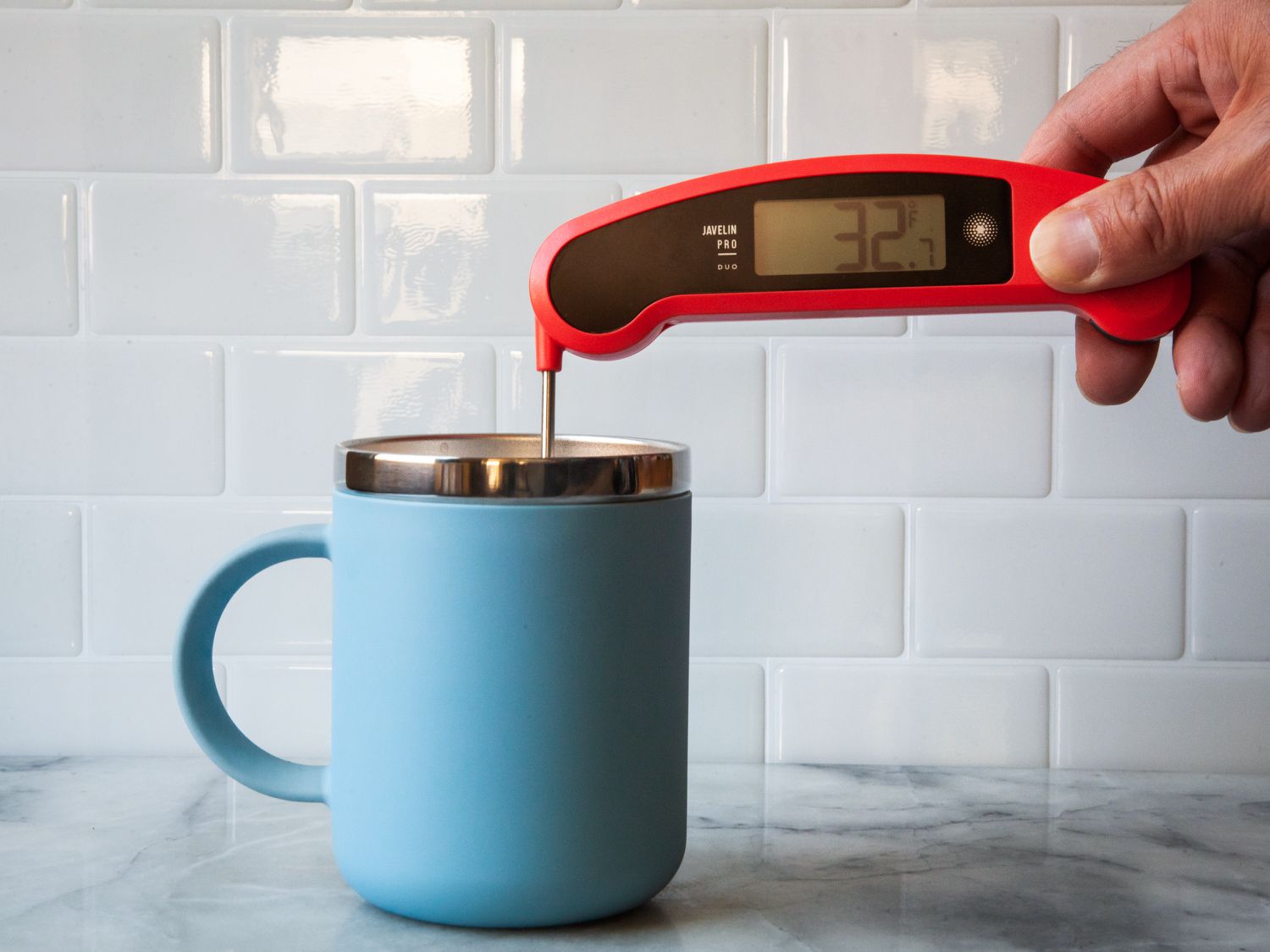 Person using Lavatools Javelin Pro Duo Digital Instant Read Thermometer to check the temperature of a drink in a blue mug