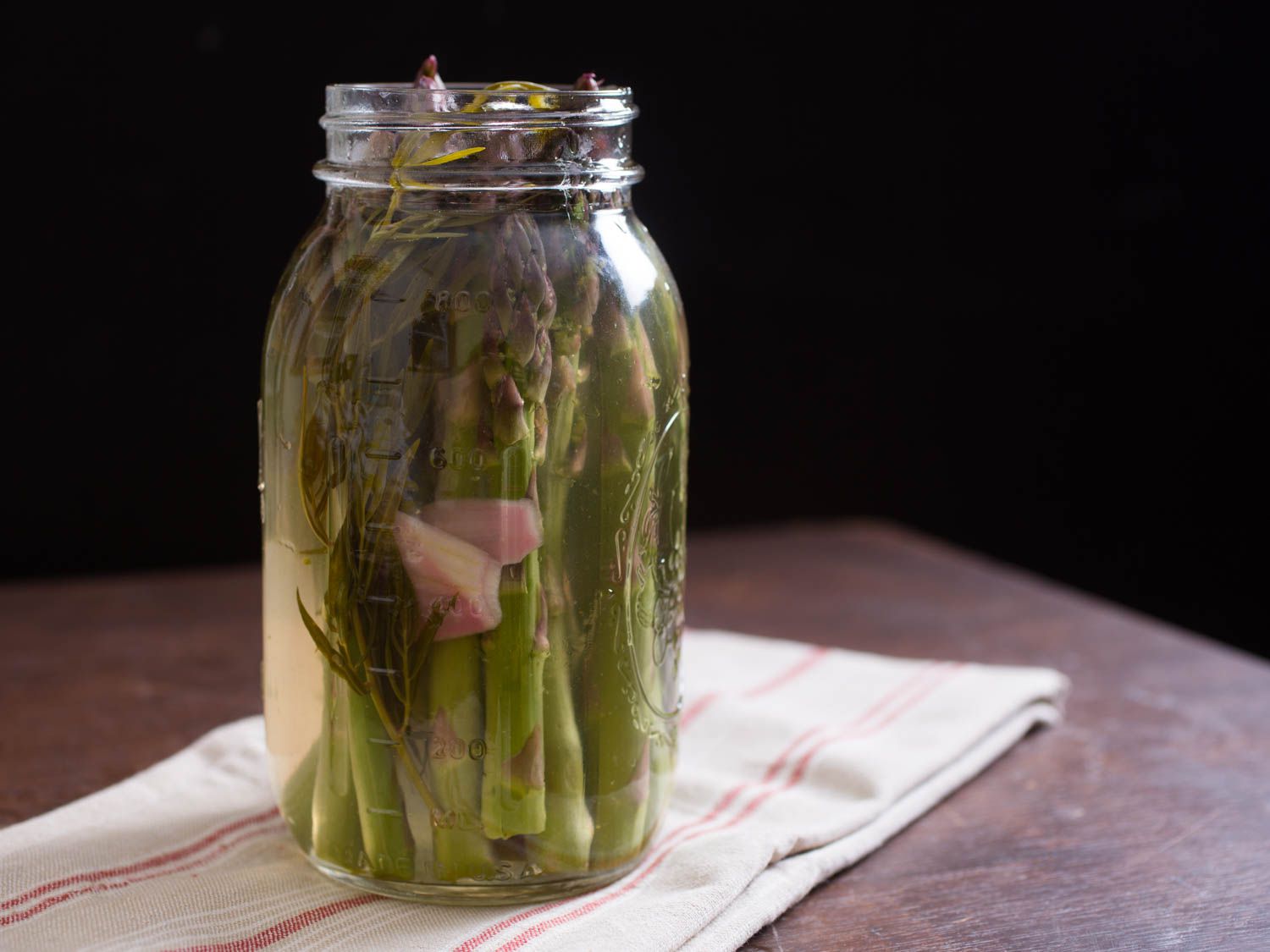  Side view of a quart jar containing Quick-Pickled Asparagus With Tarragon and Shallot