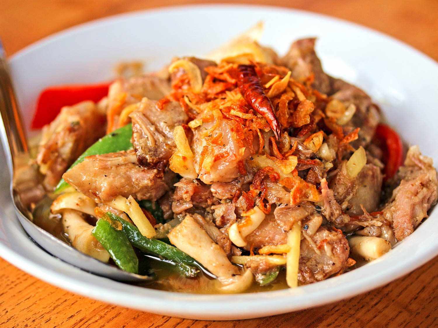 A plate of muu som: fermented pork belly with chiles and fried shallots.