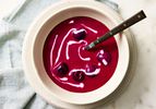 A bowl of beet and cherry soup with a swirl of sour cream