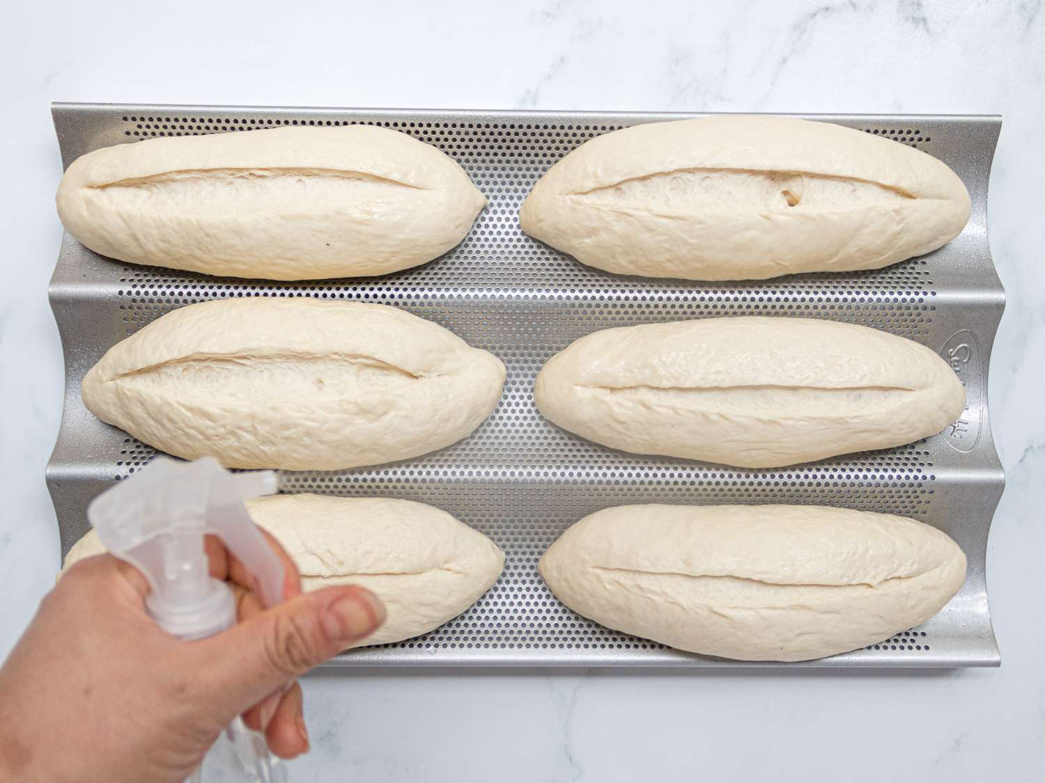 Overhead view of misting dough loaves with water