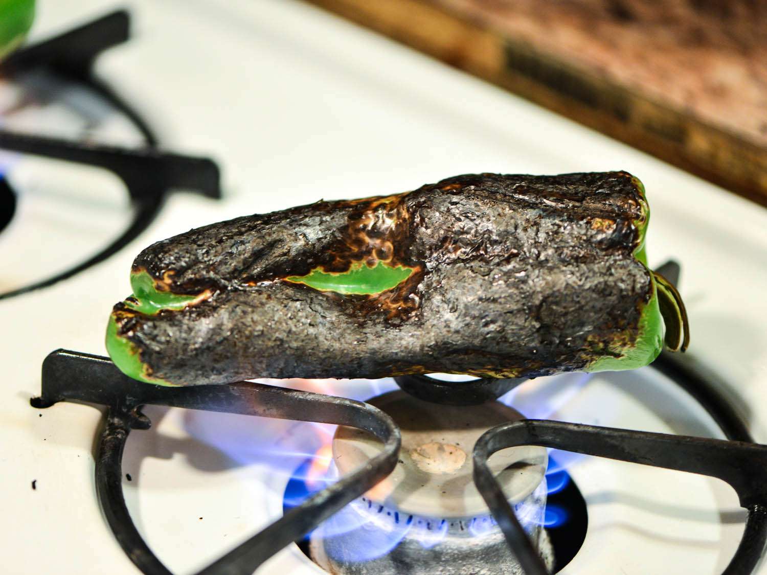 Green chile pepper charring on a stove burner