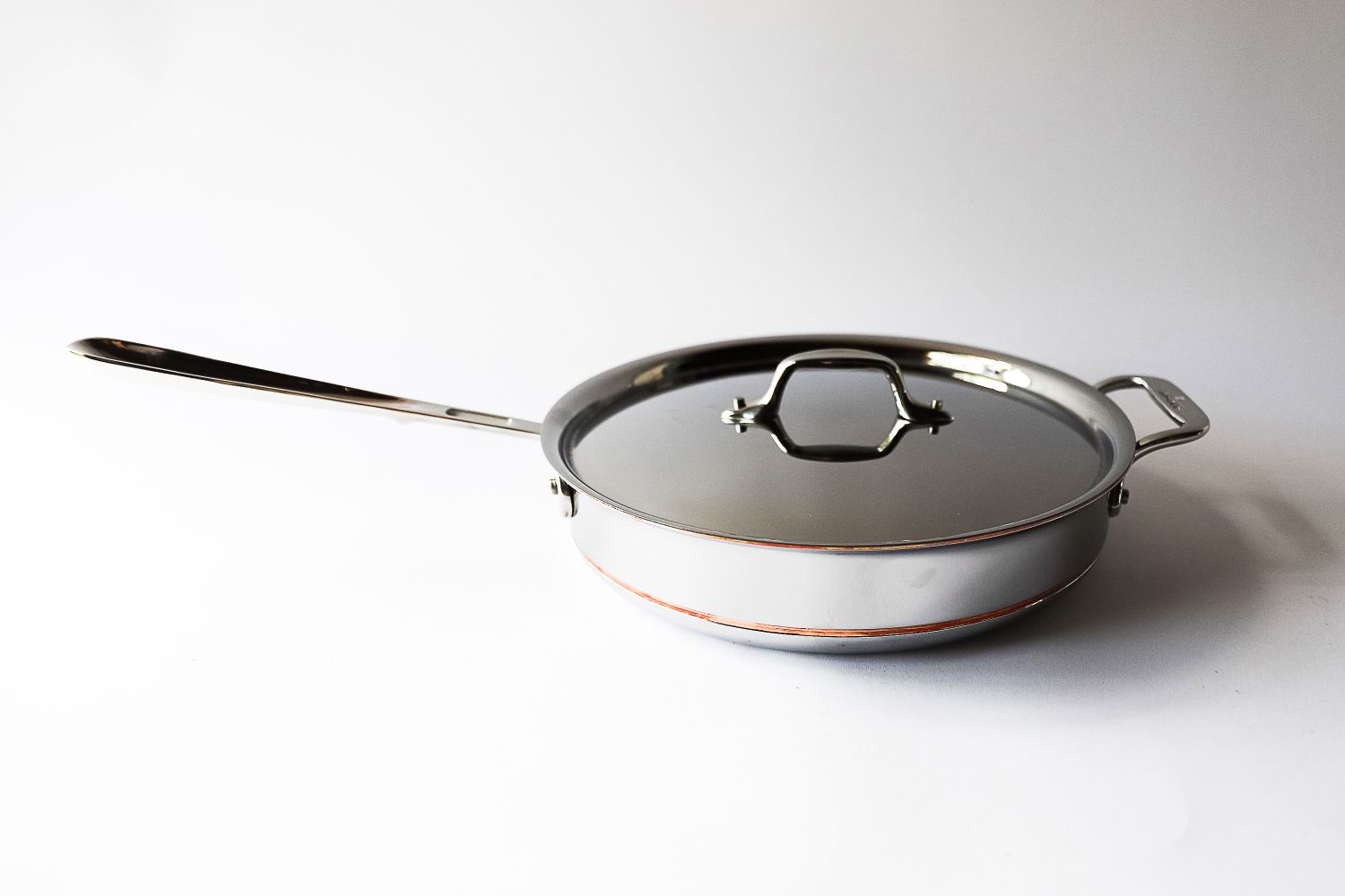 A metal frying pan with a lid long handle on the left and a side handle on the right