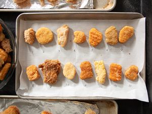 Several chicken nuggets arranged in rows on a baking sheet numbered individually from 1 to 14 for comparison purposes