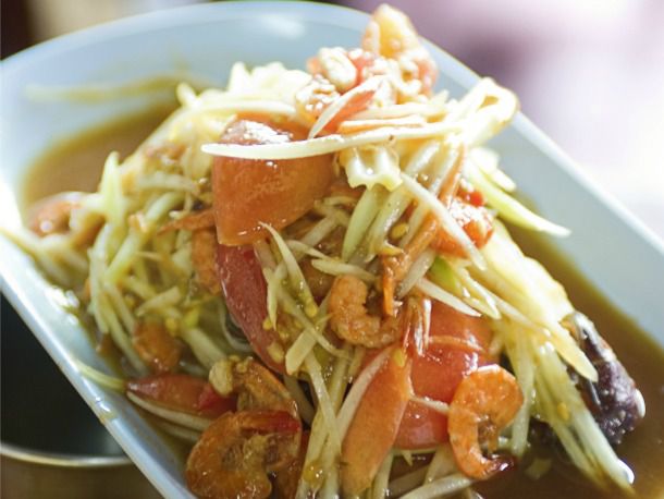 A green papaya salad piled high on a rectangular plate. 