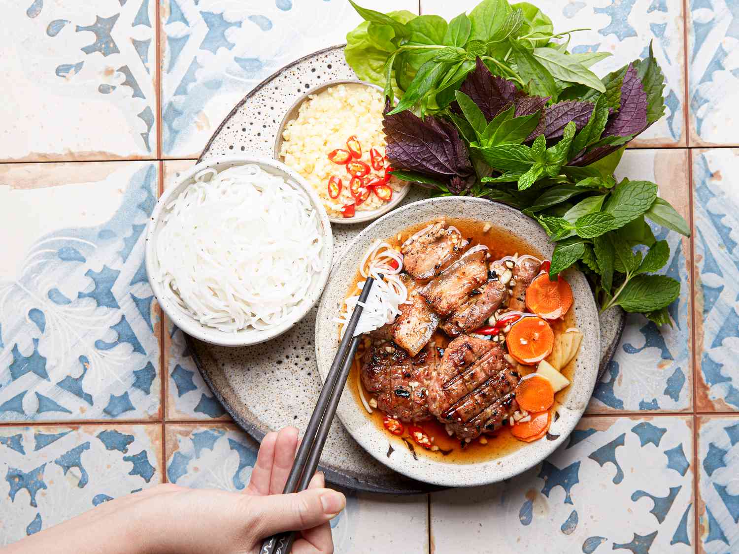 Overhead view of a hand lifting noodles of Bun Cha Hanoi