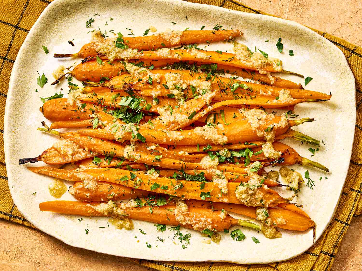 A dish of roasted carrots topped with herbs and a glaze