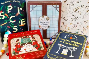 Several themed advent calendars displayed on a table featuring designs related to spices Japan chocolate and cocktails