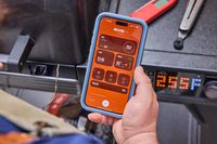 A person controls the Traeger Woodridge Pro Pellet Grill with an app on their smartphone