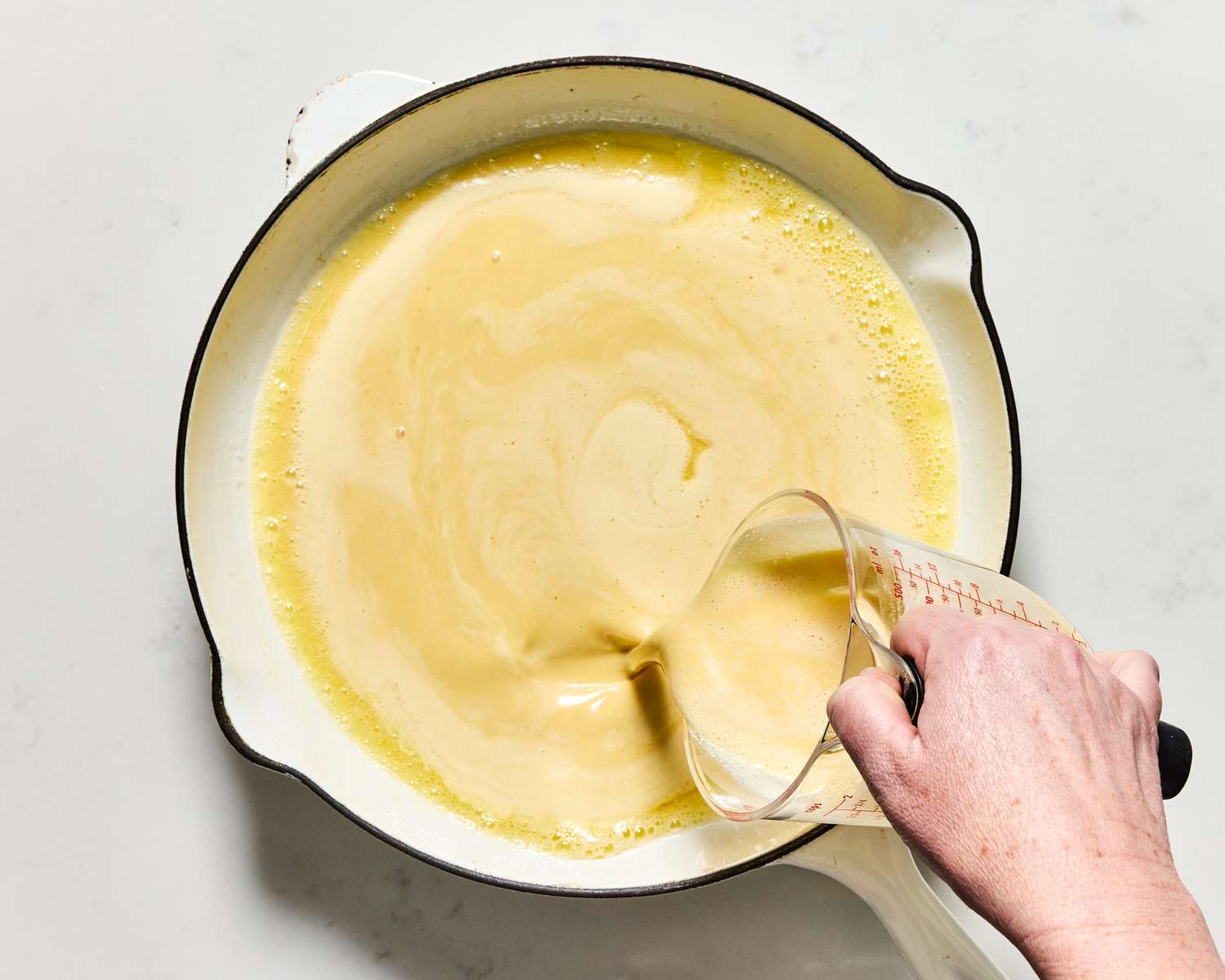 Pouring batter into a white skillet