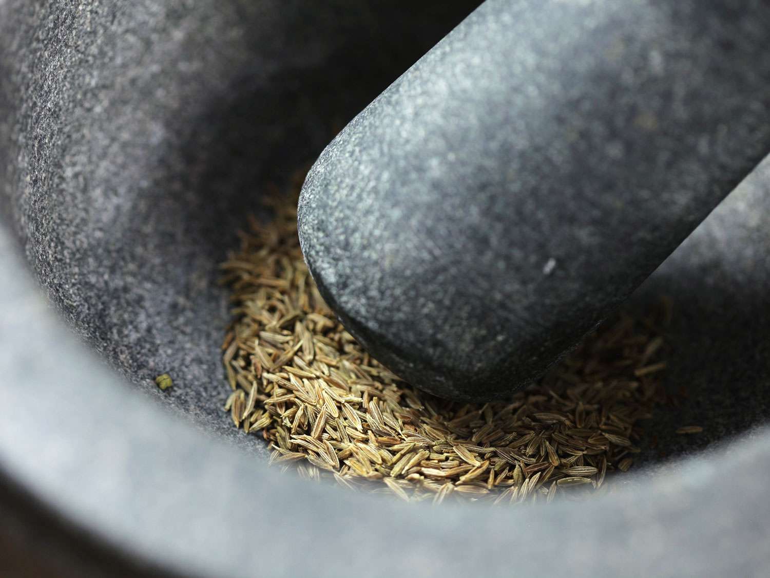 A mortar and pestle grinding toasted cumin for chile verde stew.