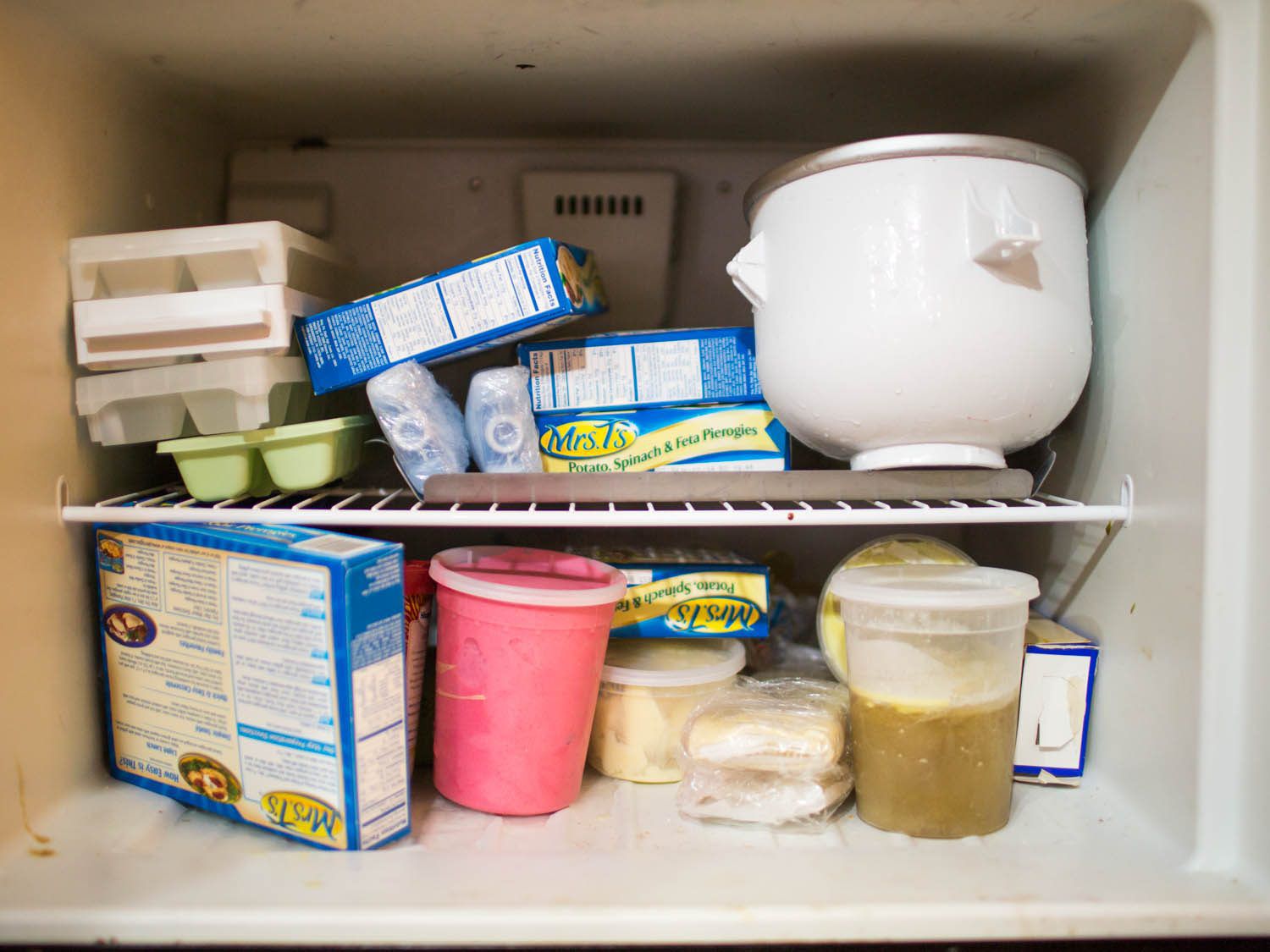 Pierogies, frozen-yogurt base, and ice cream, among other products, in a cluttered freezer