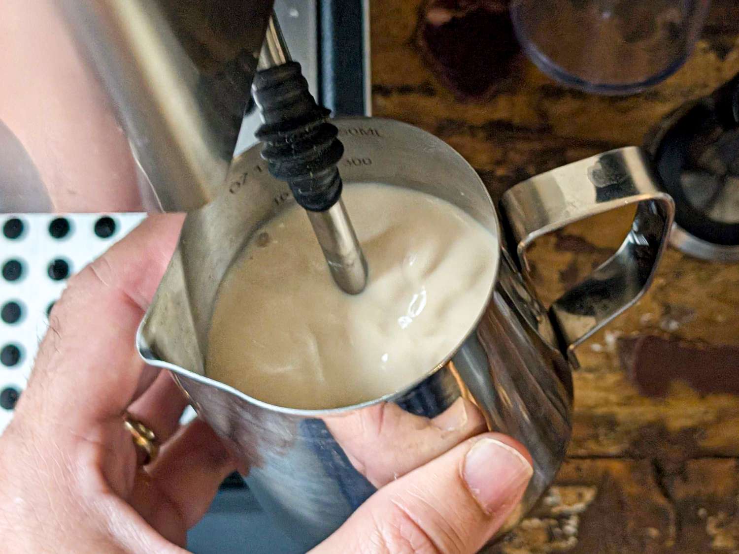 Steaming milk in a metal pitcher with a steaming wand