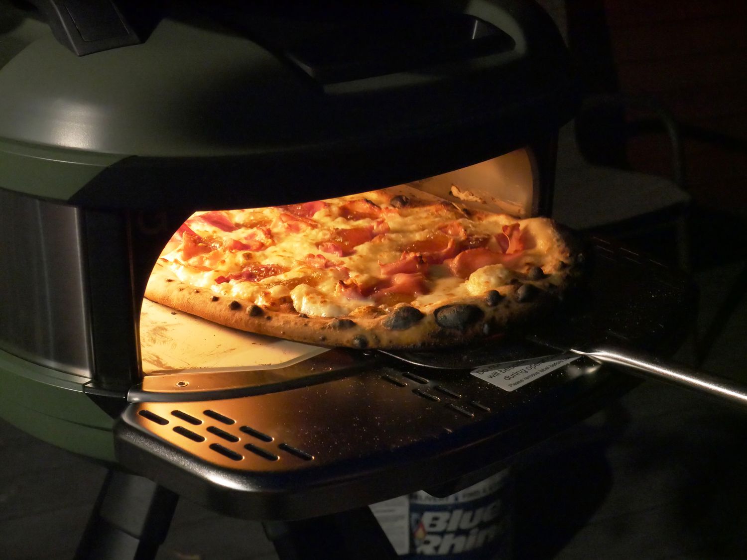 a person removing a pizza from the gozney tread