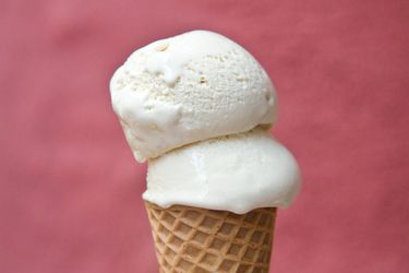 Profile closeup of a double scoop of horchata ice cream stacked into an ice cream cone.