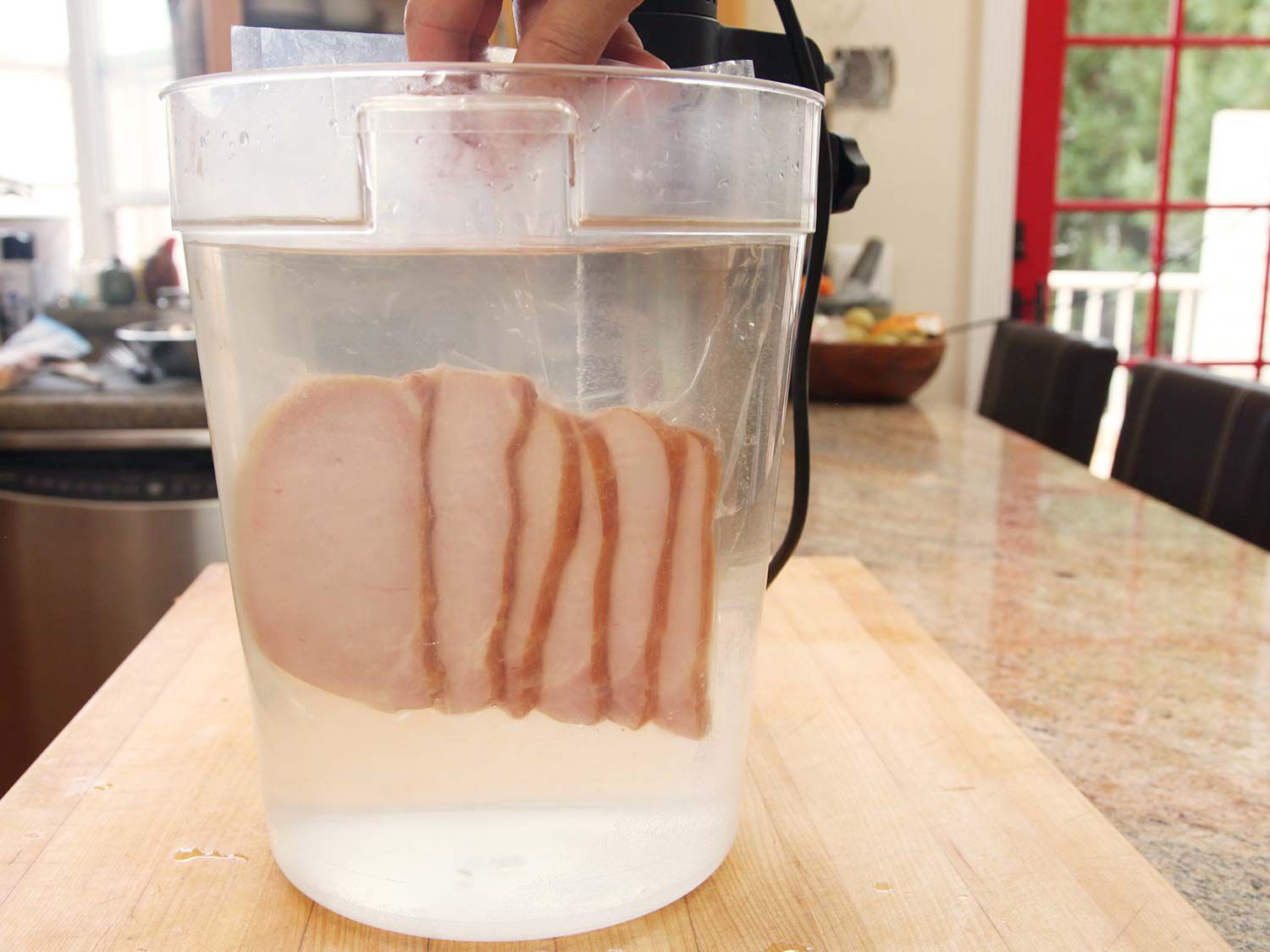 A vacuum-sealed bag of shingled Canadian bacon slices are added to the preheated water bath.