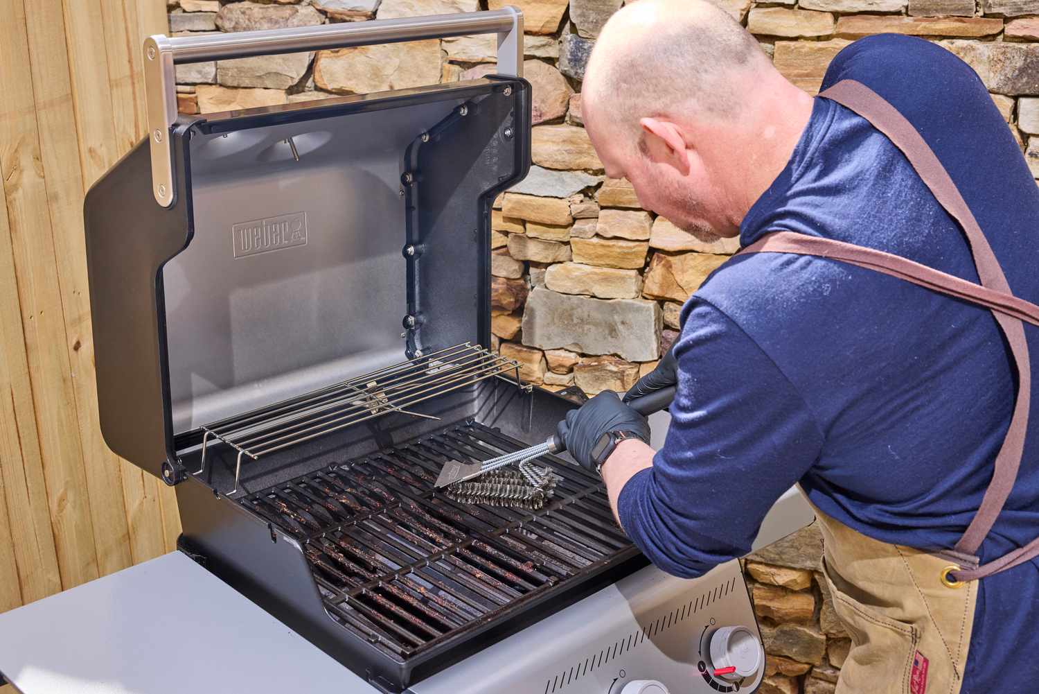 A person using a brush to clean the Weber Spirit E-310 Gas Grill