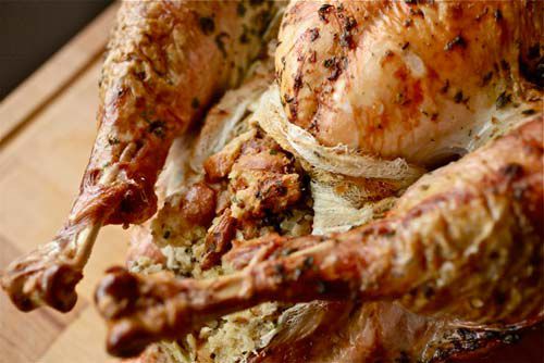 Closeup of roast turkey with crispy exposed stuffing in cheesecloth pouch 