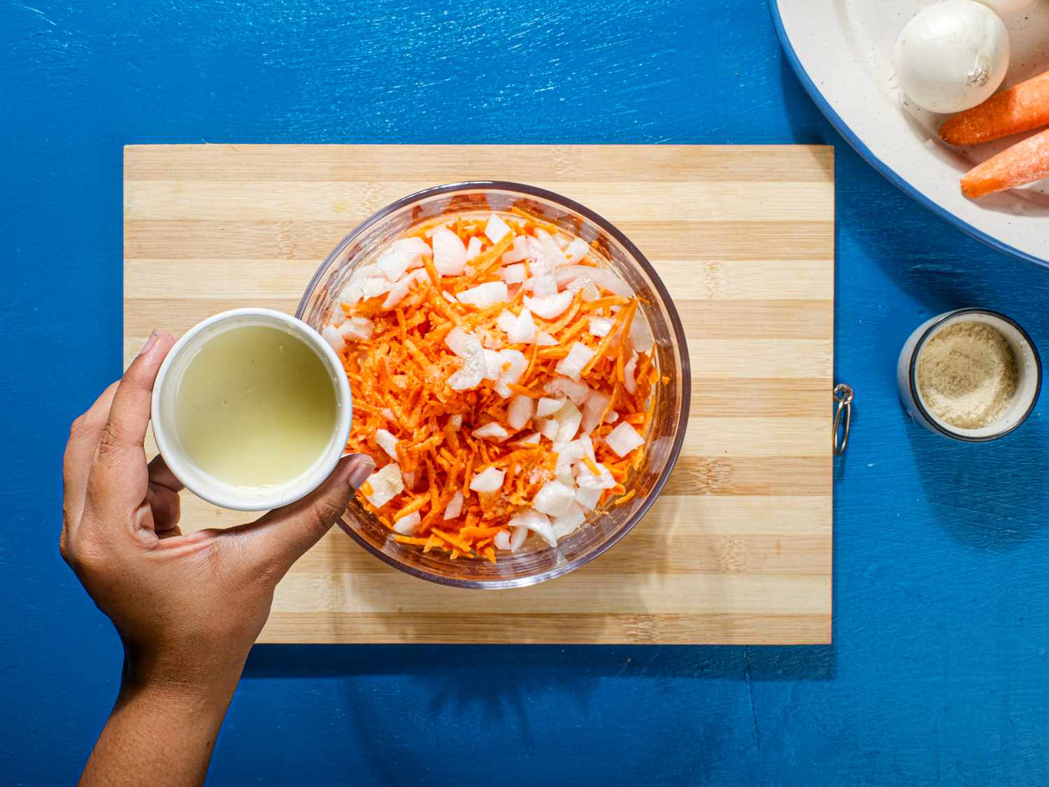 Carrot and onion are seasoned in s mixing bowl.