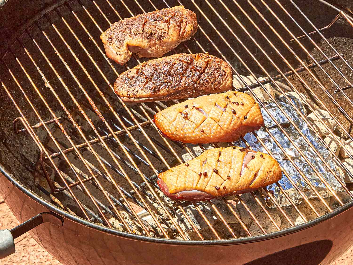 Four duck breasts smoking on a grill