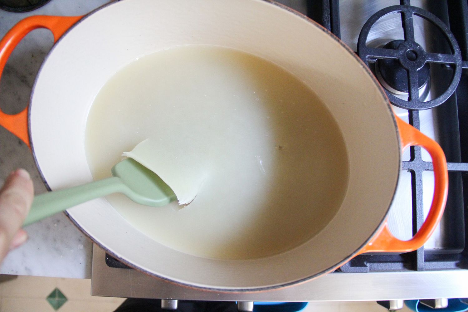 A spatula scooping solidified oil out of a pan
