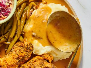 A plate featuring green beans mashed potatoes with gravy fried chicken and a side of coleslaw