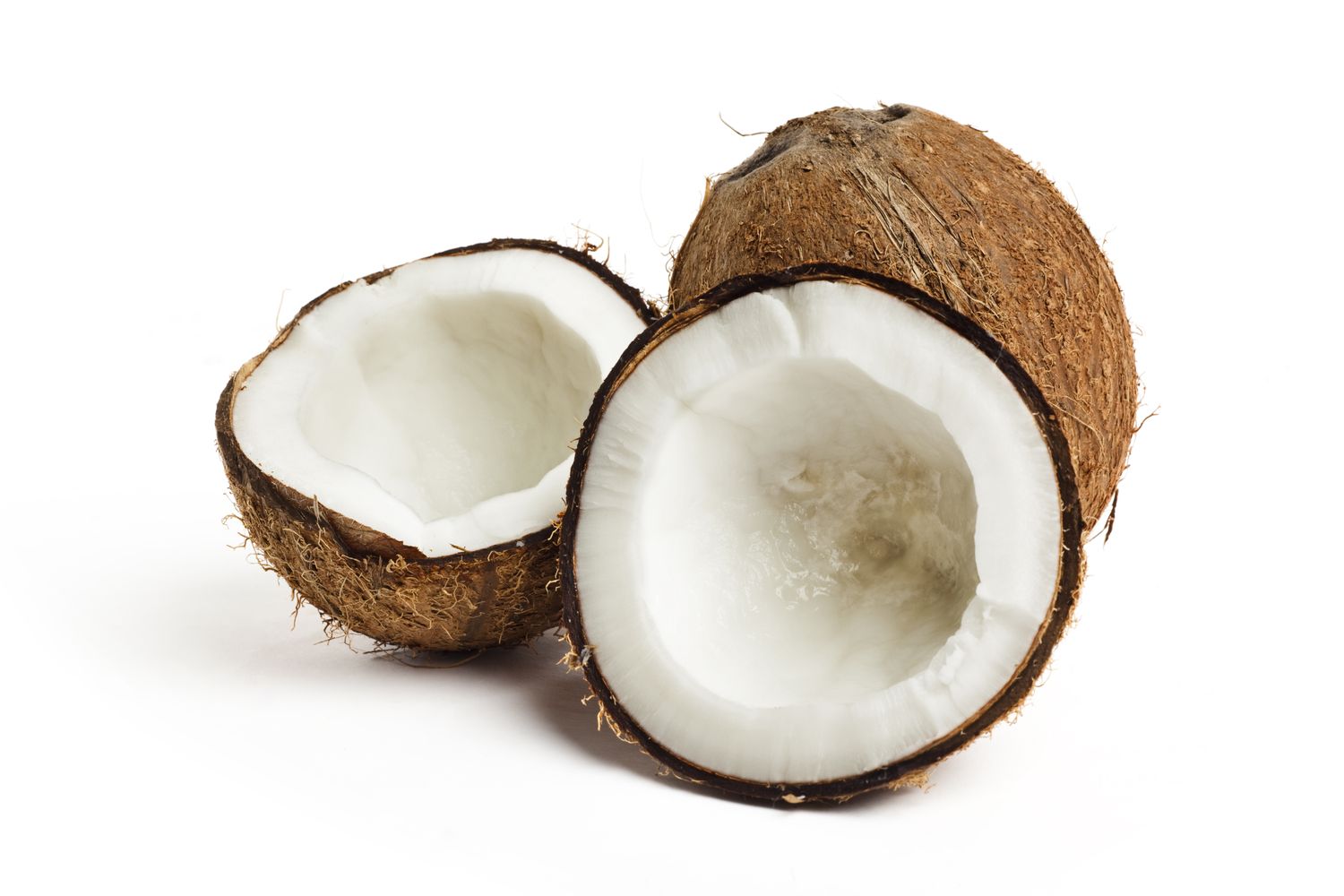 A whole coconut and a halved coconut with exposed interiors on a white background