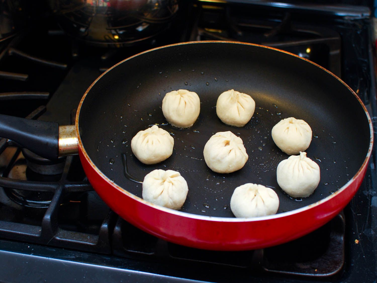 Sheng jiang bao cooking in a nonstick skillet.