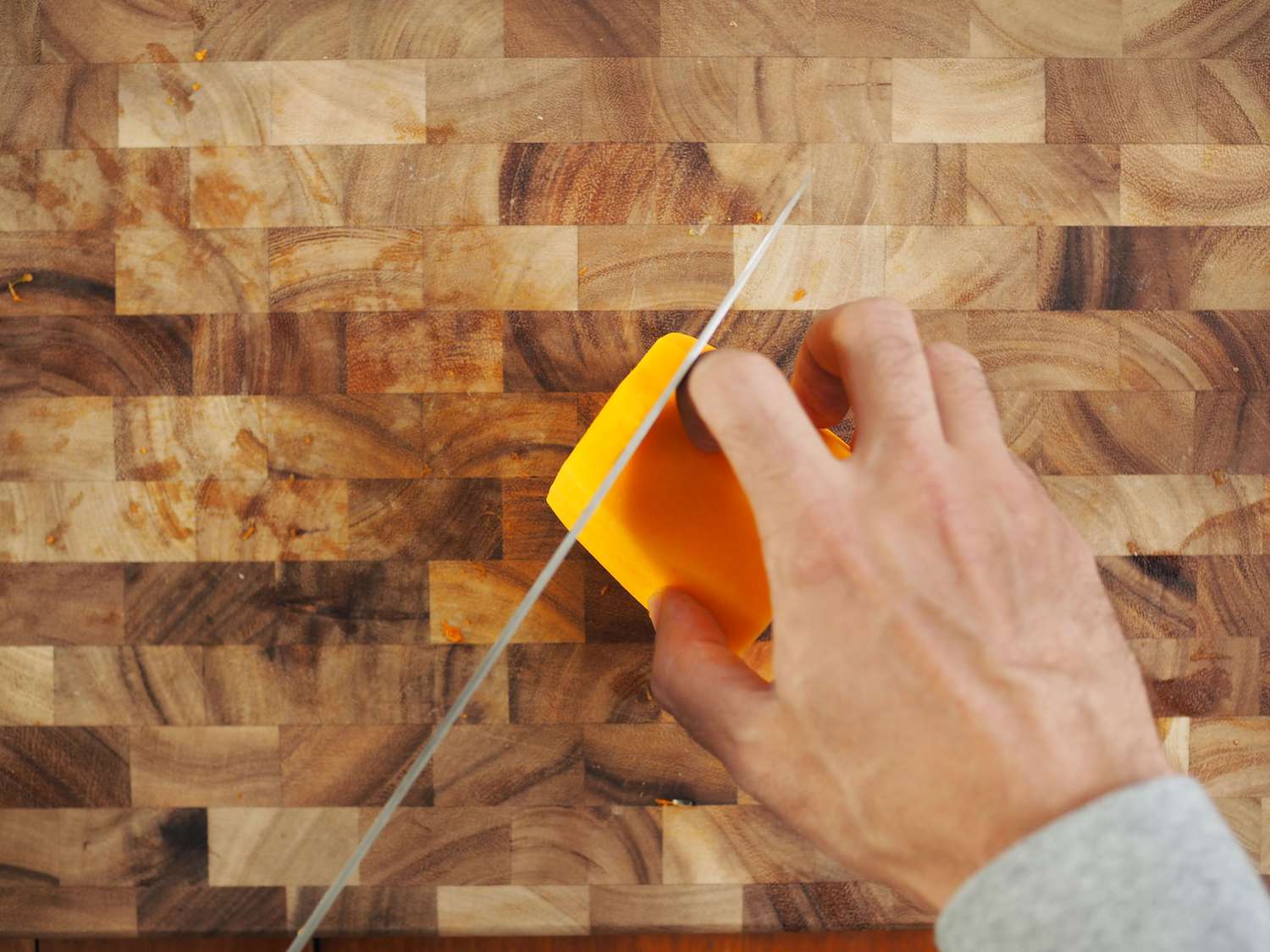 Cutting the neck of a butternut squash into thin slices.