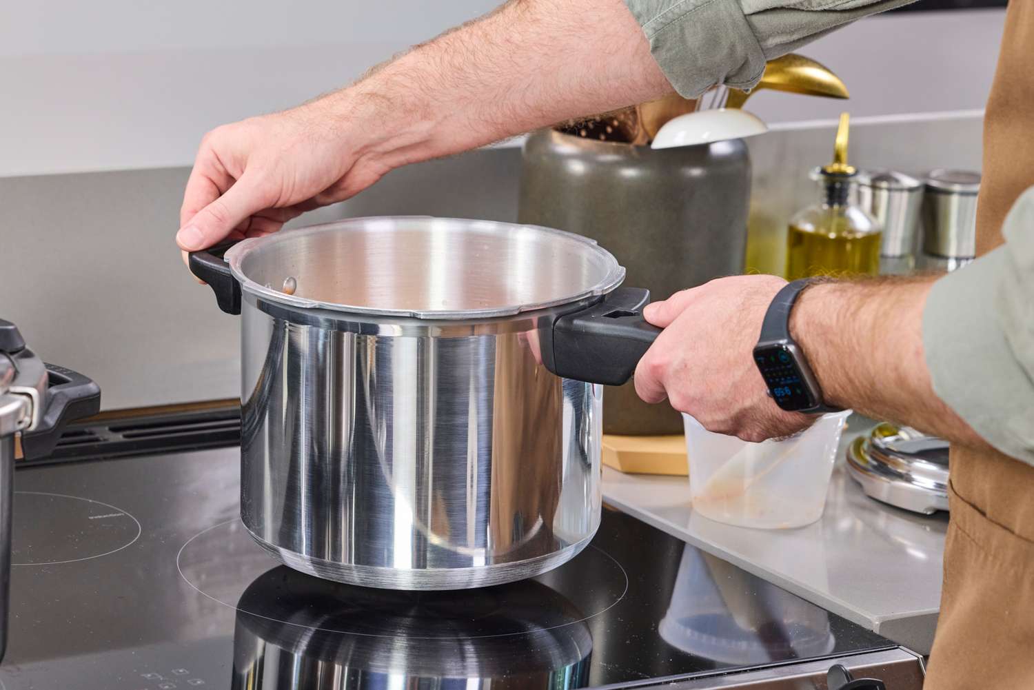 A person places the IMUSA 7 Quart Stovetop Aluminum Pressure Cooker onto a stovetop
