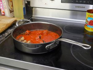 a saute pan filled with tomato sauce and meatballs