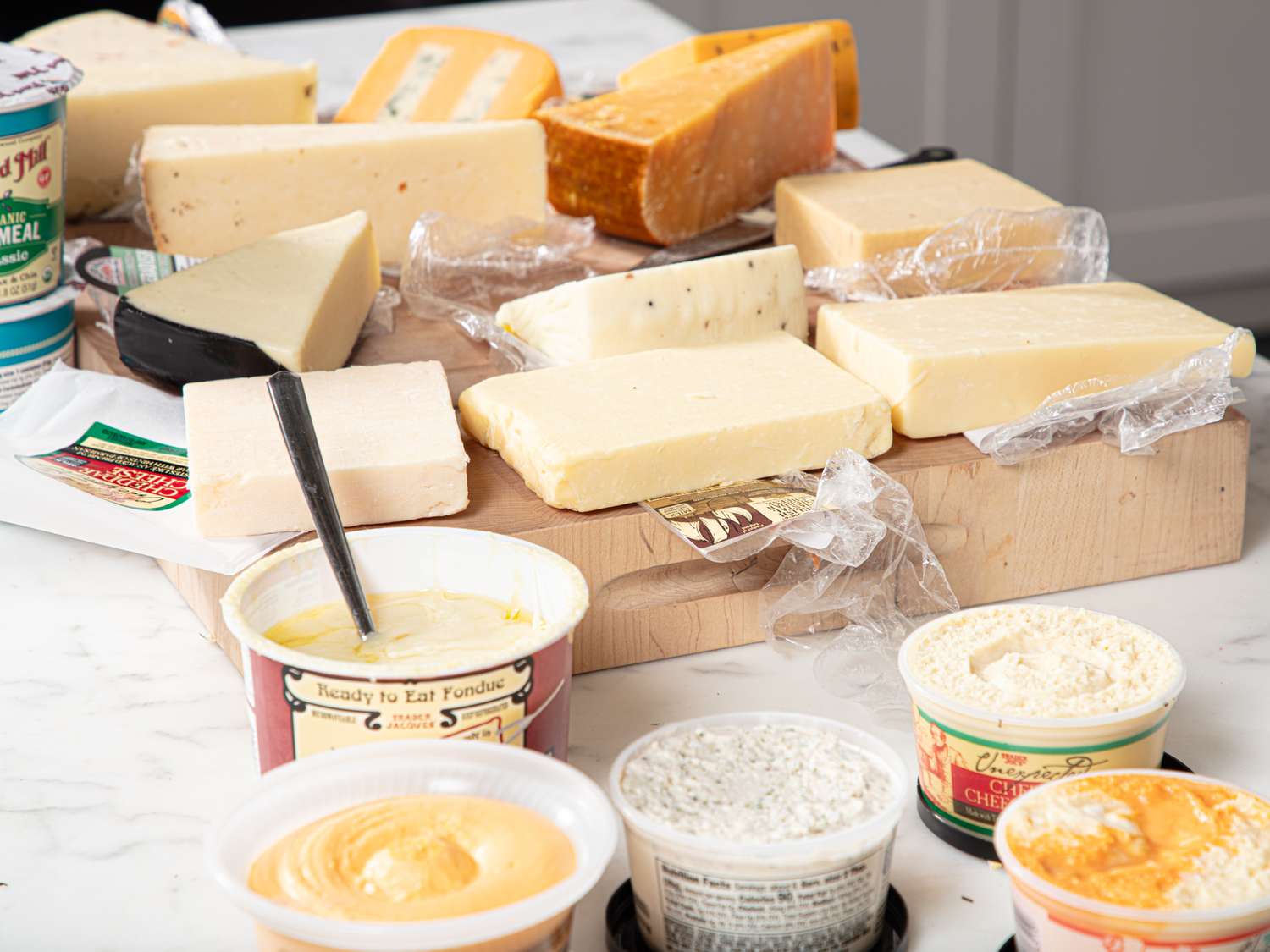 Various types of cheese and dips arranged on a table with packaging visible