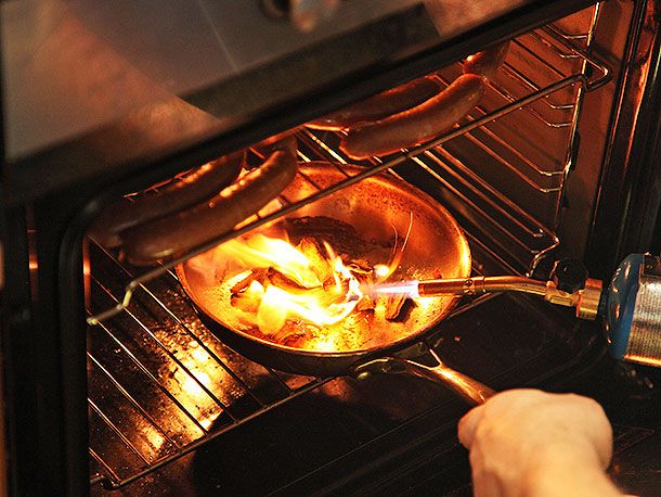 A blow torch is used to ignite several chunks of wood, then placed in the oven.