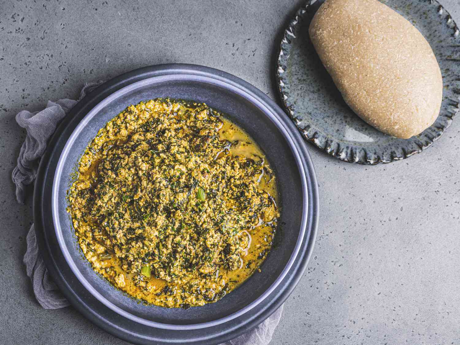 A full bowl of egusi soup served with a serving of eba.