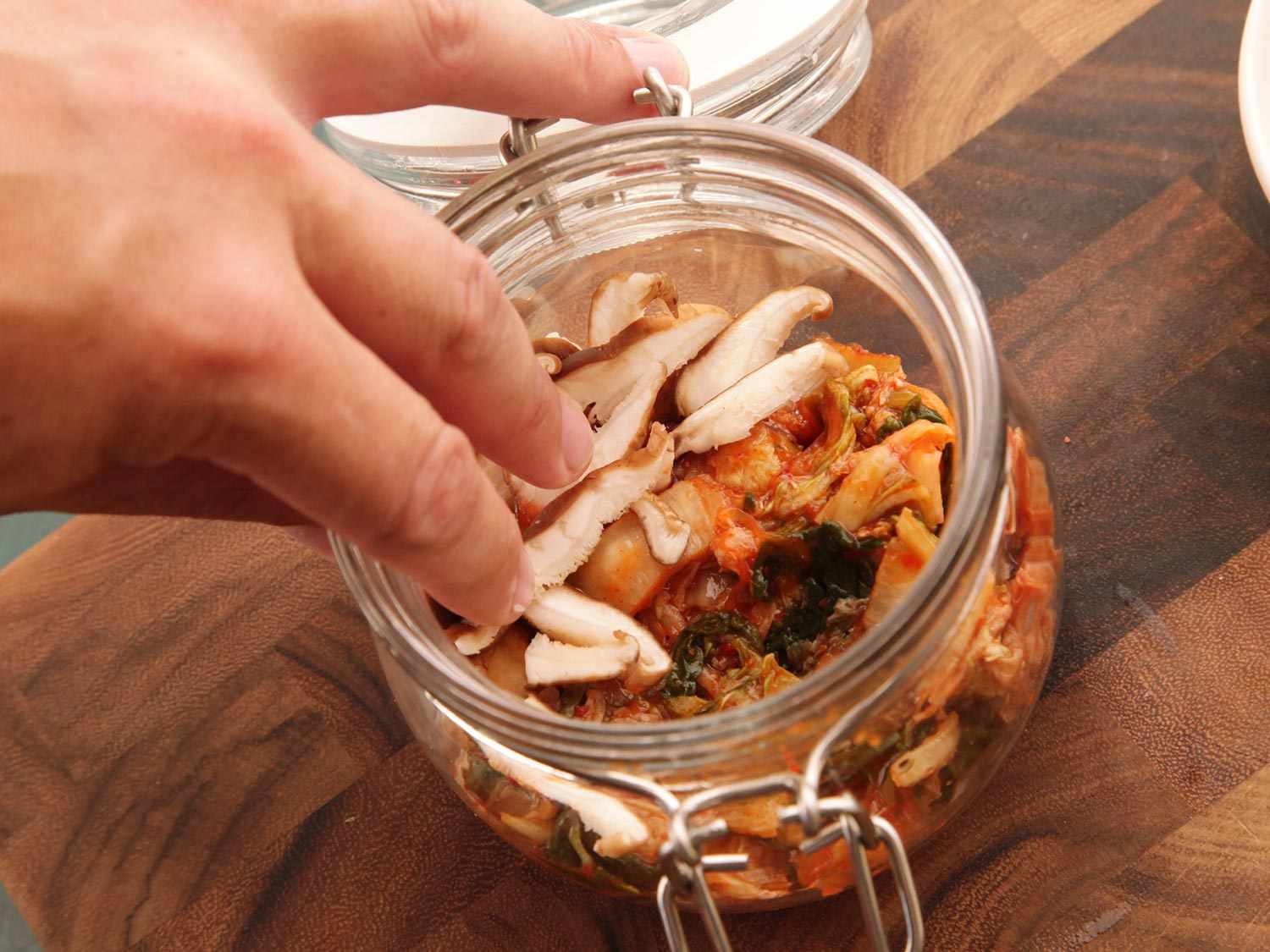 Sliced shiitake mushrooms are added to the clip top jar.